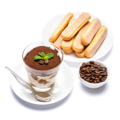 Classic tiramisu dessert in a glass cup, savoiardi cookies and coffee beans on white background with clipping path