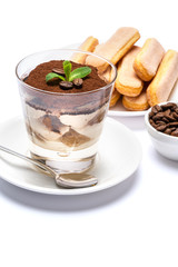 Classic tiramisu dessert in a glass cup, savoiardi cookies and coffee beans on white background with clipping path