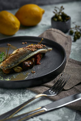 Grilled seabass with eggplant and lime. Horizontal top view, top shot. Copy space, gray concrete marble background, soft light. Food Fashion Photo.