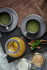 Transparent glass teapot with chitrus tea and cups, tea set on a wooden table. Close up, gray background, soft light.