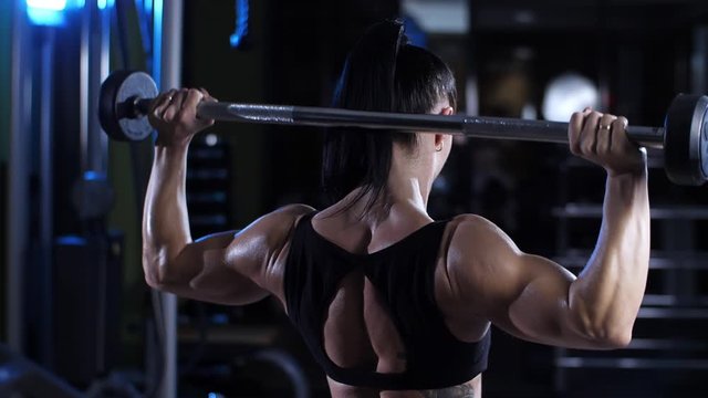 Woman lifts the barbell at gym