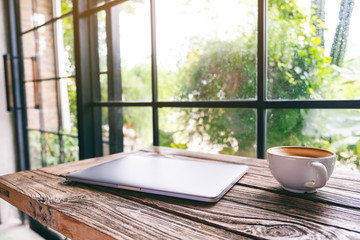 A single laptop computer with a coffee cup on wooden table