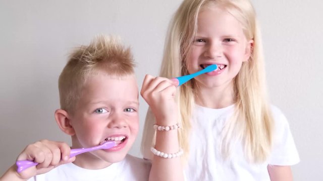 Little cute blonde girl and boy are brushing teeth. Fun lifestile play dentist game. Children smile. Health care, dental hygiene