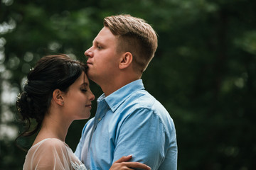 Obraz premium Beautiful bride and groom hugging and kissing on their wedding day outdoors. Concept wedding, new family.