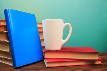  pile of old books with mug , panorma, good copy space  on blue background