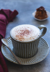 cappuccino coffee mug on saucer, milk and cake on a gray background, copy space