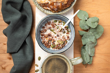 breakfast on a wooden table: granola, croissant and coffee, top view
