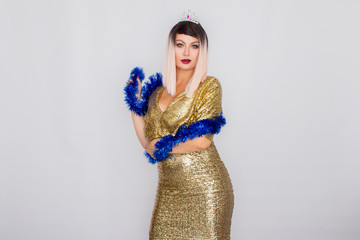 Emotional happy blonde woman in evening gold dress and with tinsel on her neck.