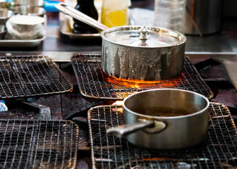 Chef cooking with flame in a frying pan on a kitchen stove.
