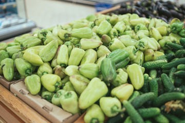 Cucumbersand and green pepper in wooden box. Fresh bell pepper green and cucumbers in wooden box with straw