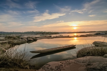 River view morning of a small boat floating in Mekong river with yellow sun light and blue sky background, sunrise at Sam Phan Bok, Ubon Ratchathani, Thailand.