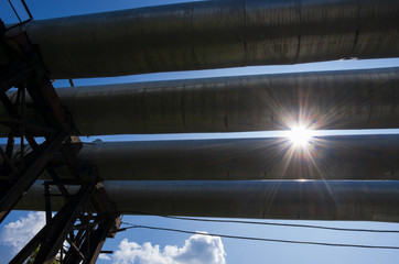 Radiant sun and four tubes of thermal power plant on the background of the blue sky