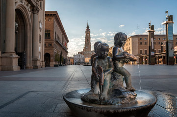 Small bronze fountain located in the plaza de El Pilar de Zaragoza, with the tower of the cathedral...