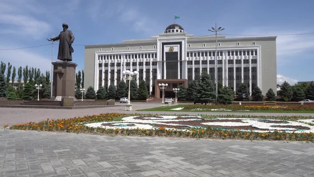  Taraz Regional Akimat City Hall with Waving Kazakh Flag at Background with Statue of Jambyl Jabayev Side View on a Sunny Blue Sky Day