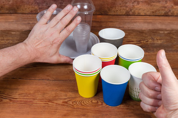 Gestures approving use disposable paper cups and renounce plastic tableware