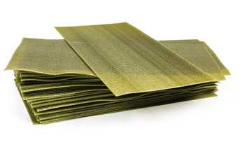 Uncooked green spinach lasagna sheets on a white background