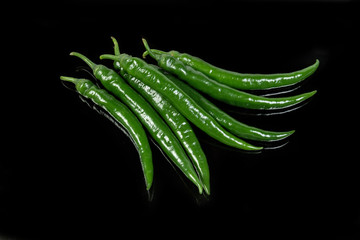 Fresh green chili peppers on a dark background