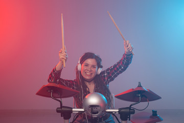 Music, hobby and people concept - sexy female brunette in headphones plays on electronic drum kit in studio