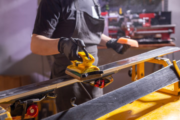 Close up of young man repairing the ski in the service
