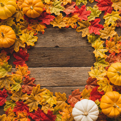 Maple leaves/leaf changing color from green to red in fall autumn seasonal over wood table...