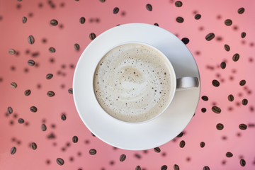  coffee in a white cup with milk foam on a pink background levitation of a cup and coffee beans 