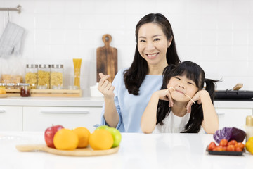 Portrait of Happy Asian family in the kitchen. Good mood Mother and Little girl Smiling at you