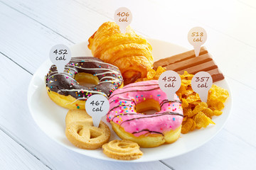 Calories counting and food control concept. doughnut ,croissant ,chocolate and cookies with label...