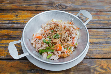 Thai breakfast with eggs fried pan with crab sticks, pork chops, white pork sausage and vegetables topping on wooden table  background,