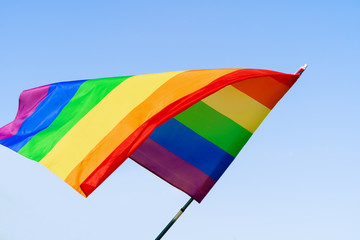 Gay rainbow flag waving in the wind in a clear blue sky