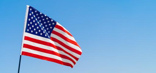 Fototapeta premium American flag waving in the wind against blue sky