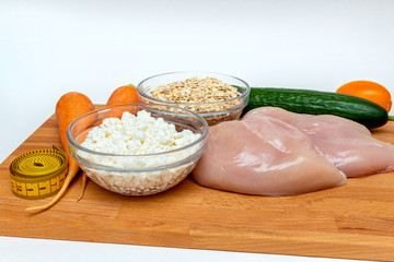 raw chicken breast, cereals, measuring tape, farm cottage cheese carrot vegetables close up on wooden background protein healthy diet fat free concept eco product sports nutrition