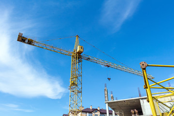 Fototapeta na wymiar Tower crane on the blue sky background. Building construction work concept, investments in the development construction buildings and structures industry.