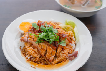 Close up rice crispy pork, roasted red pork, Scallion and boiled egg with sauce in white plate on wooden table background.