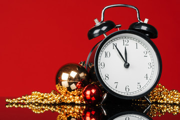 Black vintage alarm clock with christmas baubles and decor on dark black background. Christmas eve concept