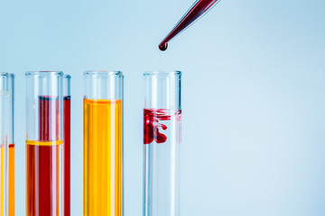 Laboratory test tubes with red and yellow liquids on light blue background