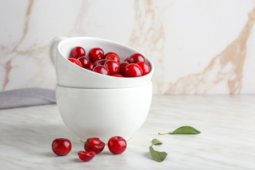 Cup with ripe sweet cherry on table