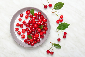 Plate with ripe sweet cherry on light background