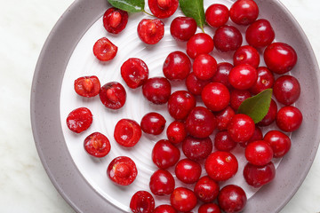 Plate with ripe sweet cherry on light background
