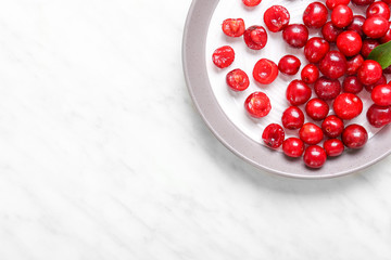 Plate with ripe sweet cherry on light background