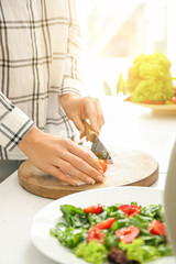 Woman preparing tasty strawberry spinach salad at table