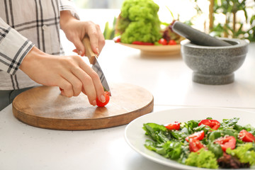 Woman preparing tasty strawberry spinach salad at table