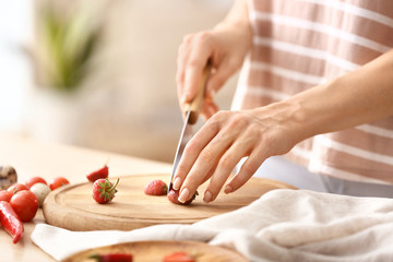 Obraz na płótnie Canvas Woman cutting fresh strawberry at table