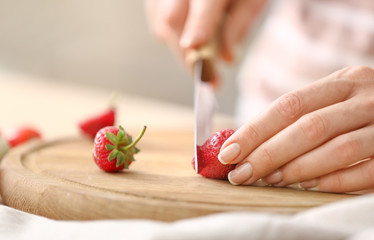 Obraz na płótnie Canvas Woman cutting fresh strawberry at table, closeup