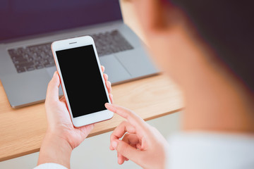 Hand holding smartphone with blank screen on table in cafe. Take your screen to put on advertising.