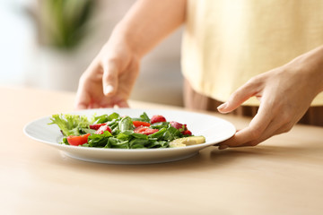 Obraz na płótnie Canvas Woman with fresh salad on plate at table, closeup