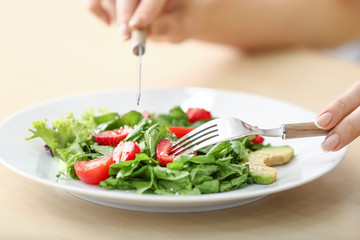 Woman eating fresh salad with strawberry and spinach at table, closeup