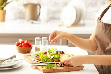 Obraz na płótnie Canvas Woman preparing tasty salad in kitchen