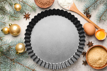 Fototapeta na wymiar Baking pan with ingredients for Christmas pie and decor on grey background