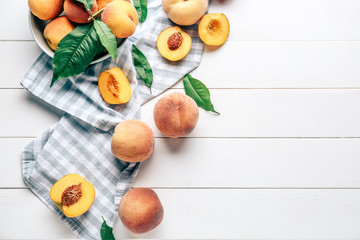 Bowl with tasty peaches on white wooden table