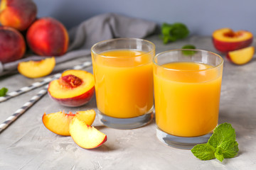 Glasses of tasty peach juice on grey table